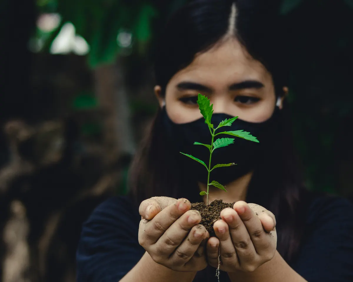 A young volunteer holding a tree seedling in a handful of soil